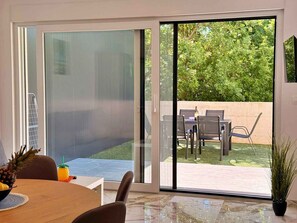 A modern dining area with a glass door leading to an outdoor patio with a table and chairs. - Holiday apartment with shared use of pool (Polje/Krk)