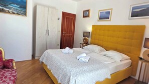 A hotel room with a bed, a wardrobe, a door, and a small table with a lamp. - Holiday apartment with shared-use pool (Baška)