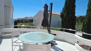 Una terraza en la azotea con una mesa de vidrio, un paraguas negro y un letrero que indica una zona VIP.