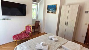 Un dormitorio con una cama, una silla, un televisor, un cuadro y un armario.