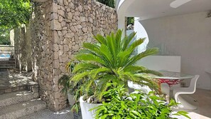 A stone wall, a white outdoor seating area, and potted plants. - Holiday apartment with shared-use pool (Baška)