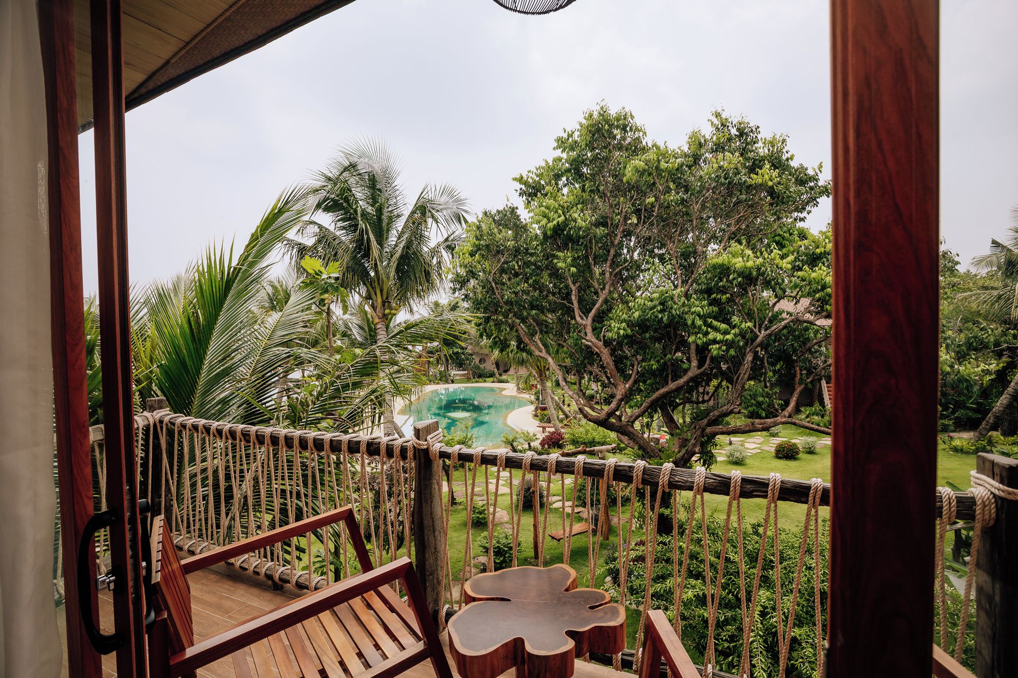 A wooden deck with a view of a swimming pool and surrounding greenery.