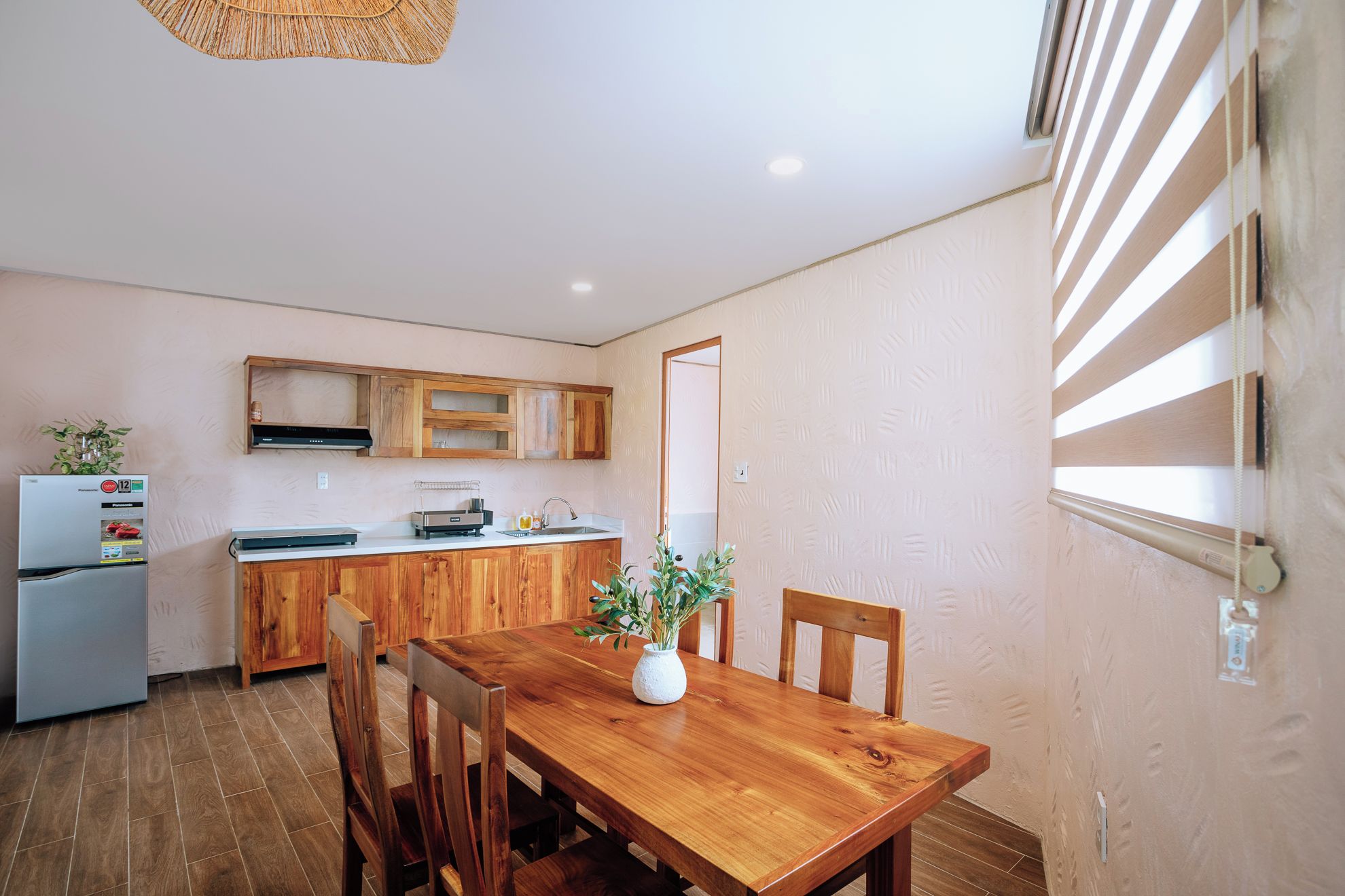A compact kitchen with wooden cabinets, a built-in oven, and a dining area with a wooden table and chairs.