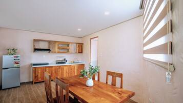A compact kitchen with wooden cabinets, a built-in oven, and a dining area with a wooden table and chairs.