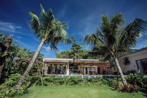 A modern house with a pool, surrounded by palm trees and lush greenery.