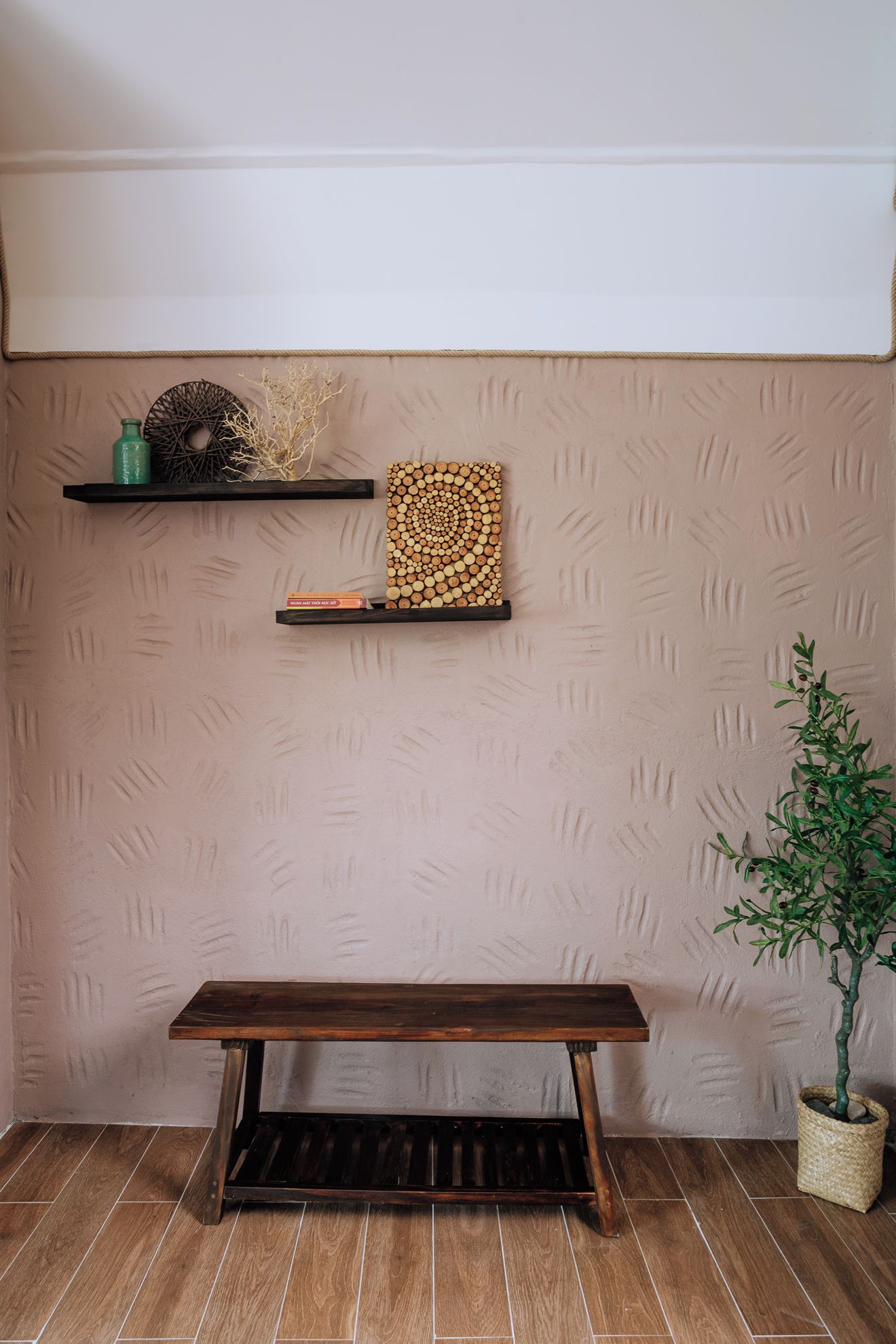 A room with a wooden bench, two shelves with decorative items, and a textured wall.