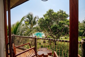 Deck de madeira com vista para uma piscina e vegetação exuberante.