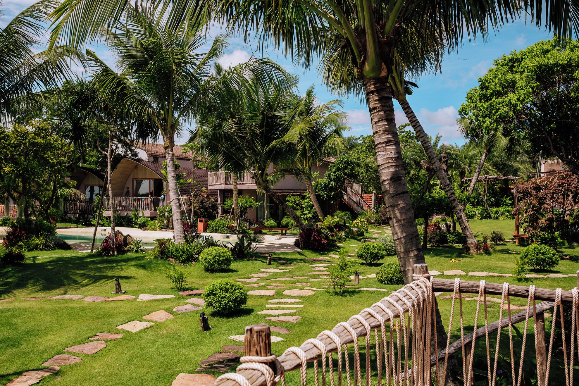 Un resort tropical con piscina, palmeras y una valla de madera.