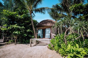 A small, single-story structure with a thatched roof, surrounded by dense tropical vegetation.