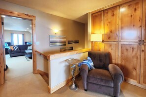 A room with a wooden cabinet, a sofa, a lamp, and a painting on the wall. - Luxurious Home Sits Right on the Beach! Pet Friendly! (Waldport)