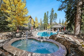 A pool area with a hot tub, lounge chairs, and a stone wall. - Mountain Thunder Lodge 1403: Ski-in/out-Resort Amenities-New Listing! (Breckenridge)