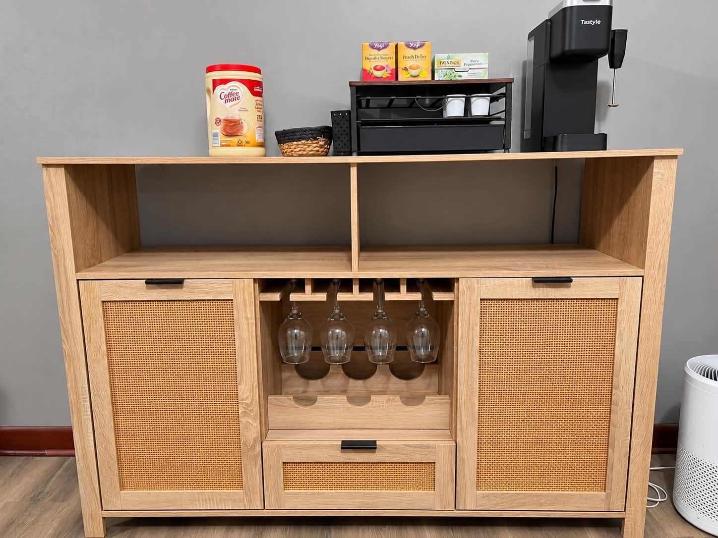 A wooden cabinet with a coffee machine, a container of coffee, and a box of yogurt.