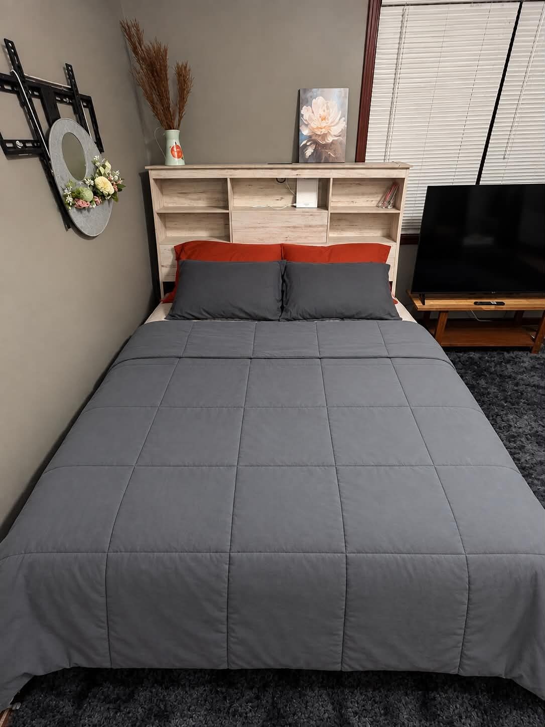 A bedroom with a bed, a TV, and a shelf with decorative items.