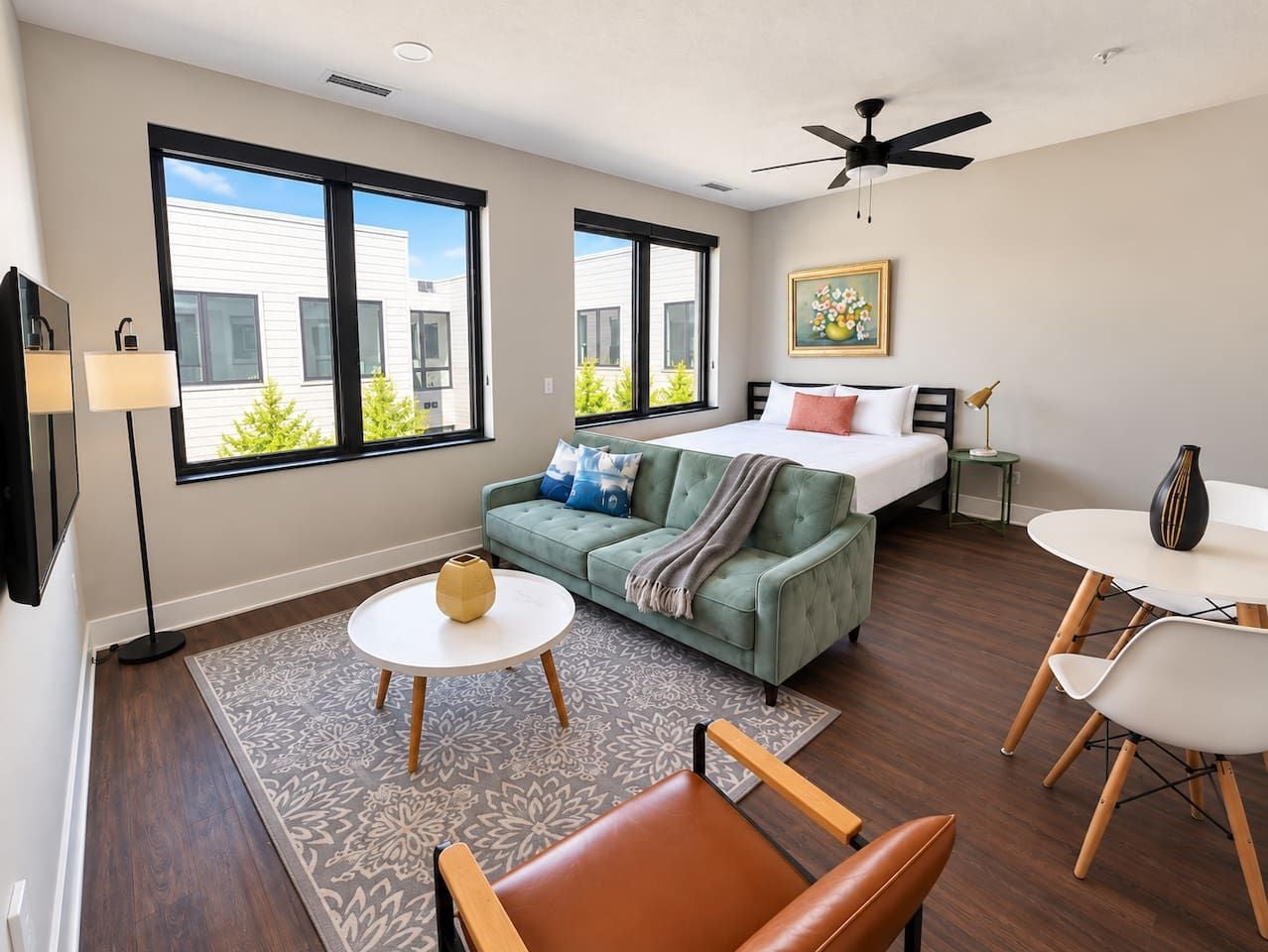 A modern living room with a sofa, a dining table, and a bed.