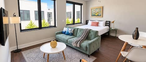 A modern living room with a sofa, a dining table, and a bed.
