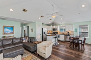 A modern living space with a sofa, armchair, dining table, and kitchen area. - 5 Minute Walk To Beach (Bolivar Peninsula)