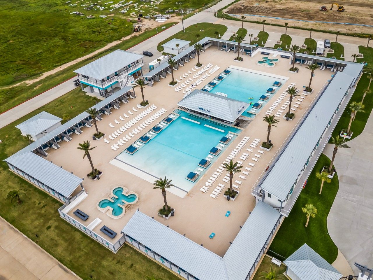 A resort with two large swimming pools, a separate children's pool, and multiple lounge areas with sun loungers.