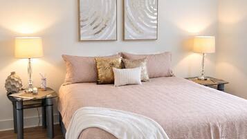 Une chambre à coucher avec un lit, deux tables de chevet, des lampes et des œuvres d’art abstraites accrochées au mur.