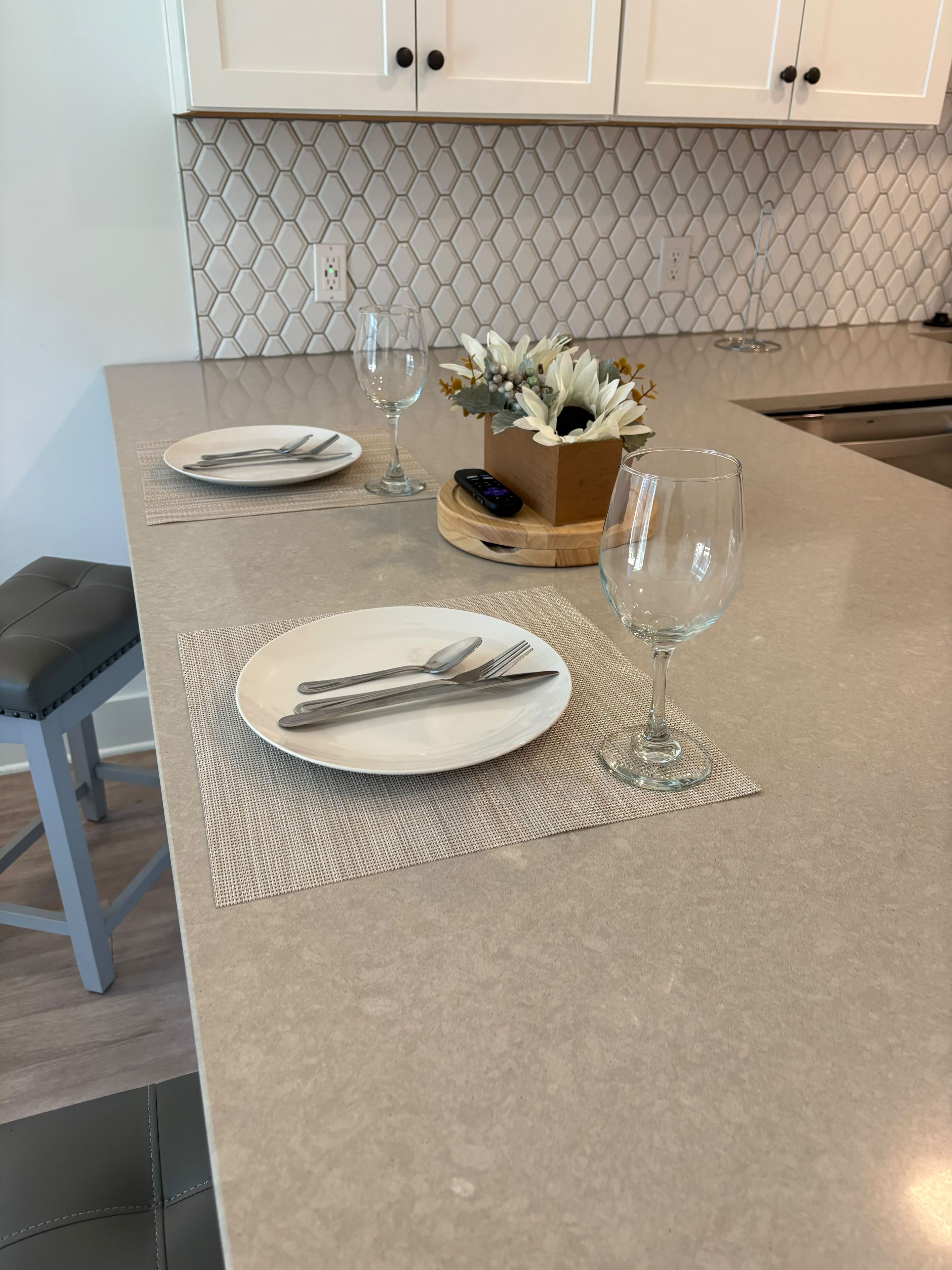 A kitchen island with two round dining tables set with plates, cutlery, and wine glasses.