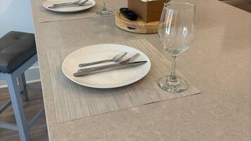 A kitchen island with two round dining tables set with plates, cutlery, and wine glasses.