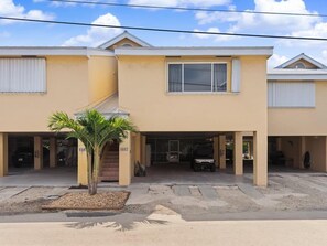 A two-story building with a flat roof, a covered parking area, and a palm tree in the foreground. - Marea - Key Largo Near Bay, Outdoor Lounge, Pool - Tennis Access (Key Largo)