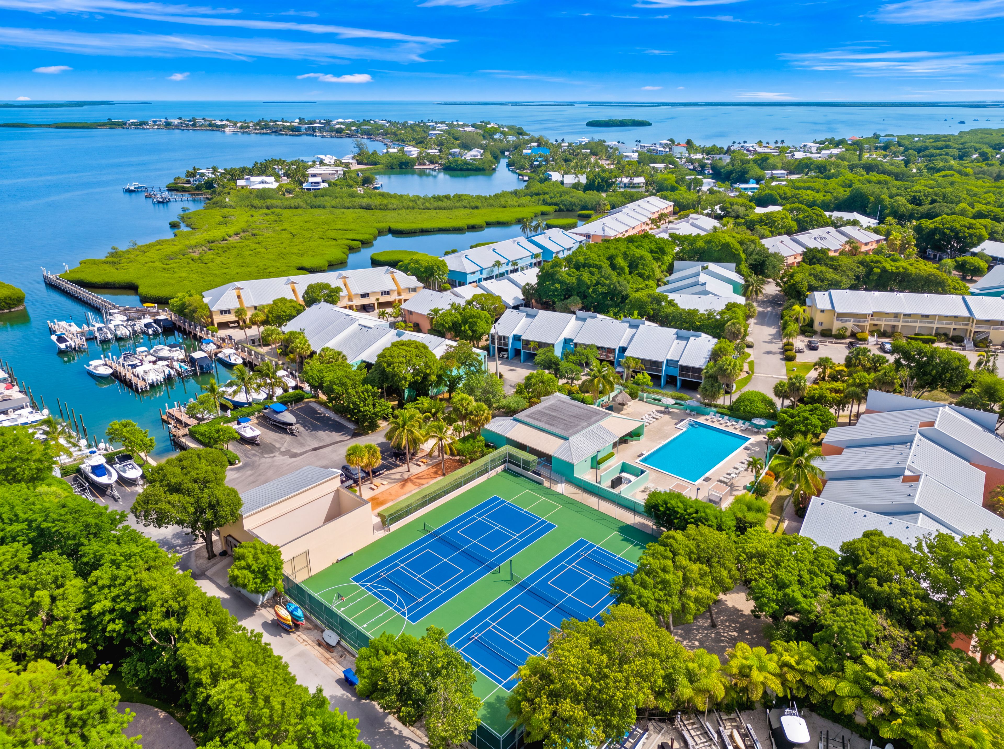 A coastal resort with a marina, tennis courts, and lush greenery.