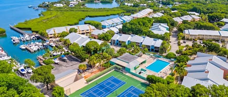 A coastal resort with a marina, tennis courts, and lush greenery.