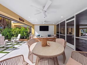 A modern outdoor dining area with wicker furniture, a ceiling fan, and a large TV on the wall. - Marea - Key Largo Near Bay, Outdoor Lounge, Pool - Tennis Access (Key Largo)