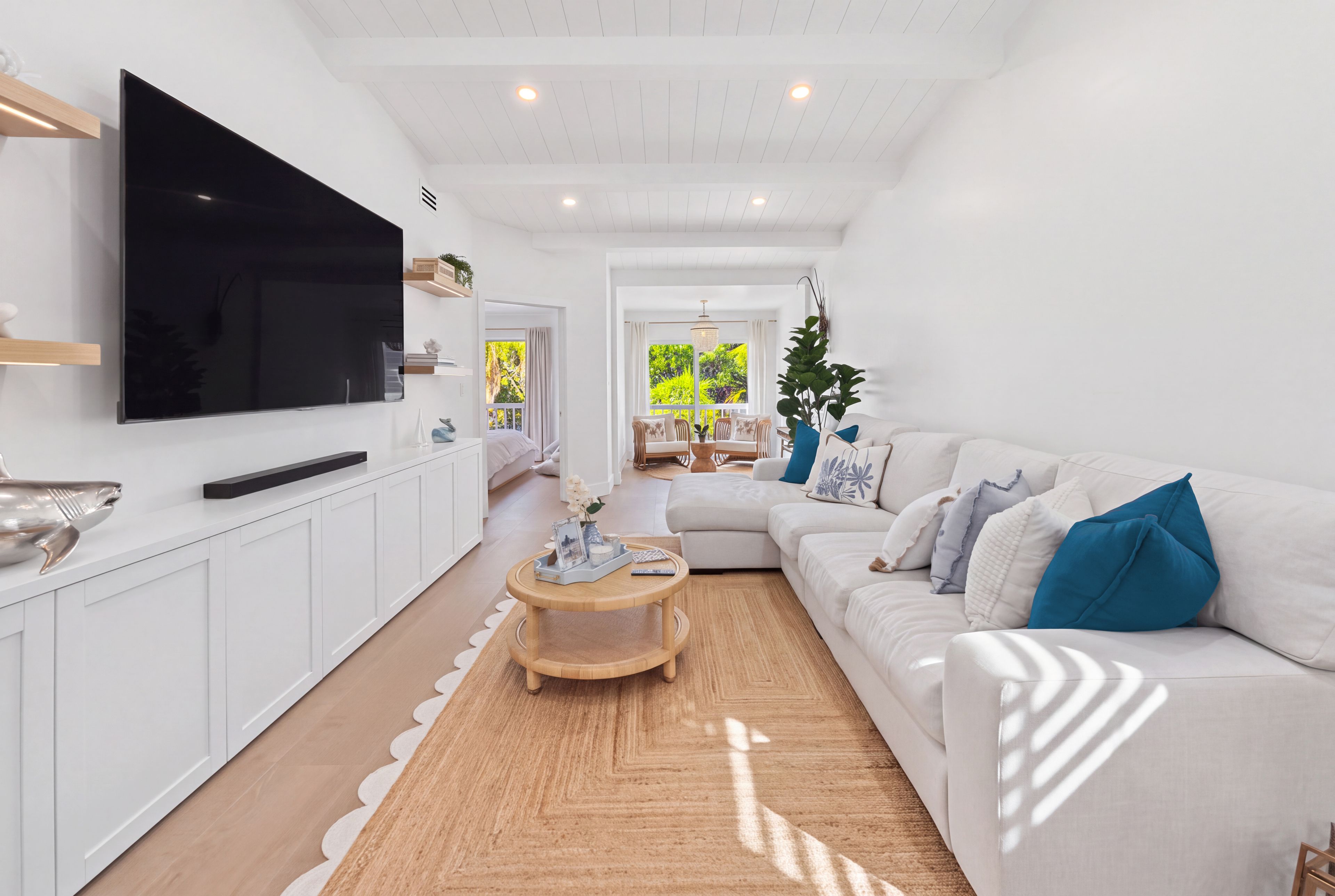 A modern living room with a flat-screen TV, a white sofa, and a wooden coffee table.