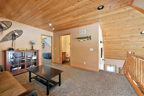 A wooden interior with a living area, a bookshelf, a fish decoration, and a staircase. - Musky Haven-Your Northwoods Gathering Spot (Hayward)