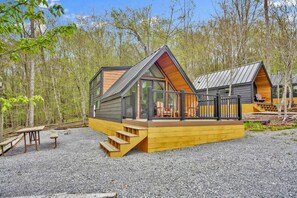 A cabin with a deck, wooden steps, and a picnic table.