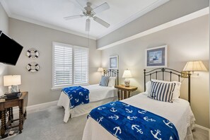 A bedroom with two beds, a ceiling fan, a TV, and a desk with a lamp. - Oceanfront | Private Balcony | Luxury Ocean Place Condo Next to the Ritz (Fernandina Beach)