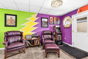 A room with two leather chairs, a bookshelf, a Pac-Man arcade machine, and colorful wall art. - Bertha's Bungalow - Sleeps 8/Dog-Friendly (Superior)