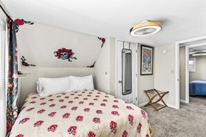 Ein Hotelzimmer mit Bett, Tür, Spiegel, Deckenventilator und Duschvorhang.