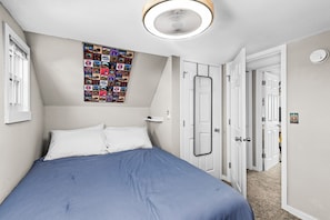 A bedroom with a bed, a wall-mounted light fixture, a door, and a wall with a photo collage. - Bertha's Bungalow - Sleeps 8/Dog-Friendly (Superior)