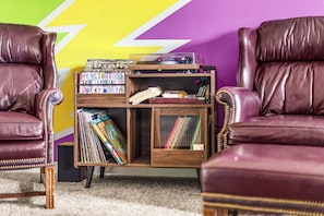 A room with two leather armchairs, a wooden side table with a record player, and a shelf with books and records. - Bertha's Bungalow - Sleeps 8/Dog-Friendly (Superior)
