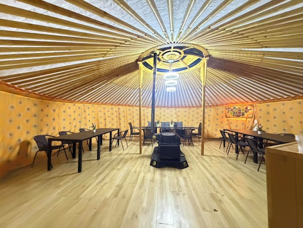 Una yurta con suelo de madera, varias mesas y sillas dispuestas para comer.