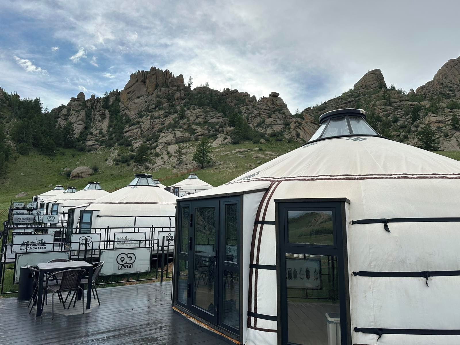 Yurtas con zona de comedor y mesas, con montañas al fondo.