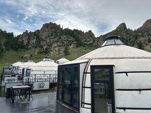Yurtas con zona de comedor y mesas, con montañas al fondo.
