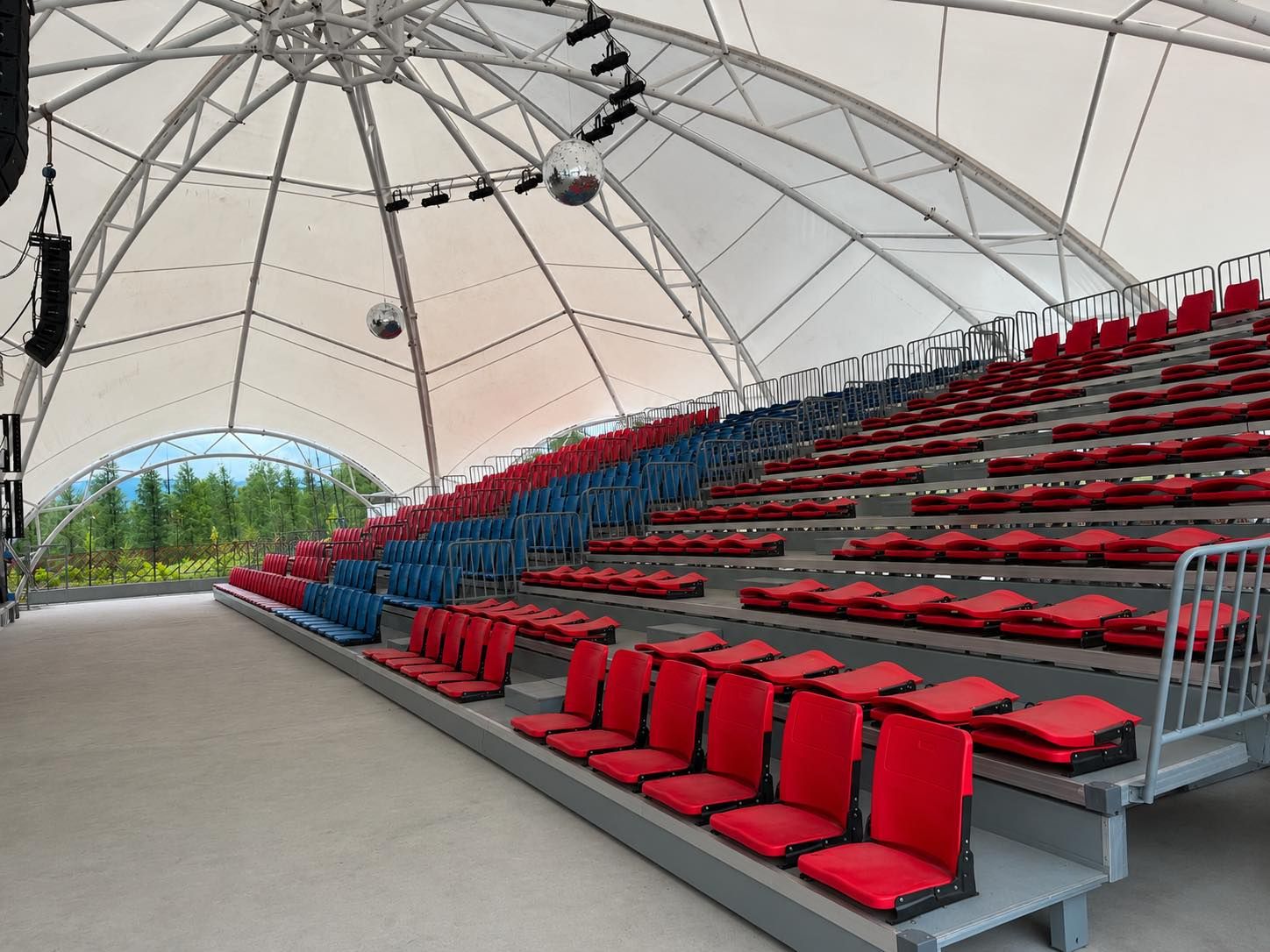 Un anfiteatro interior con asientos escalonados, una gran estructura en forma de cúpula y un área de escenario.