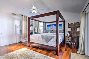 A bedroom with a four-poster bed, a ceiling fan, a large window with a view, and a decorative wall panel. - Haze Estate: Weddings, Events, Pool, Lake & Bar (Bonita Springs)