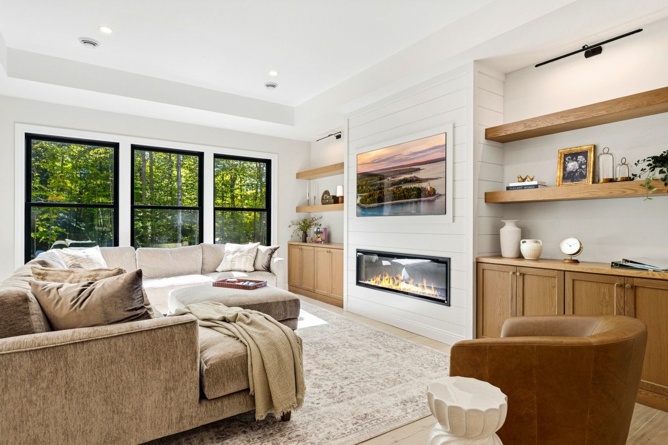 A modern living room with a fireplace, large windows, and a cozy seating area.