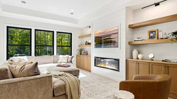 A modern living room with a fireplace, large windows, and a cozy seating area.