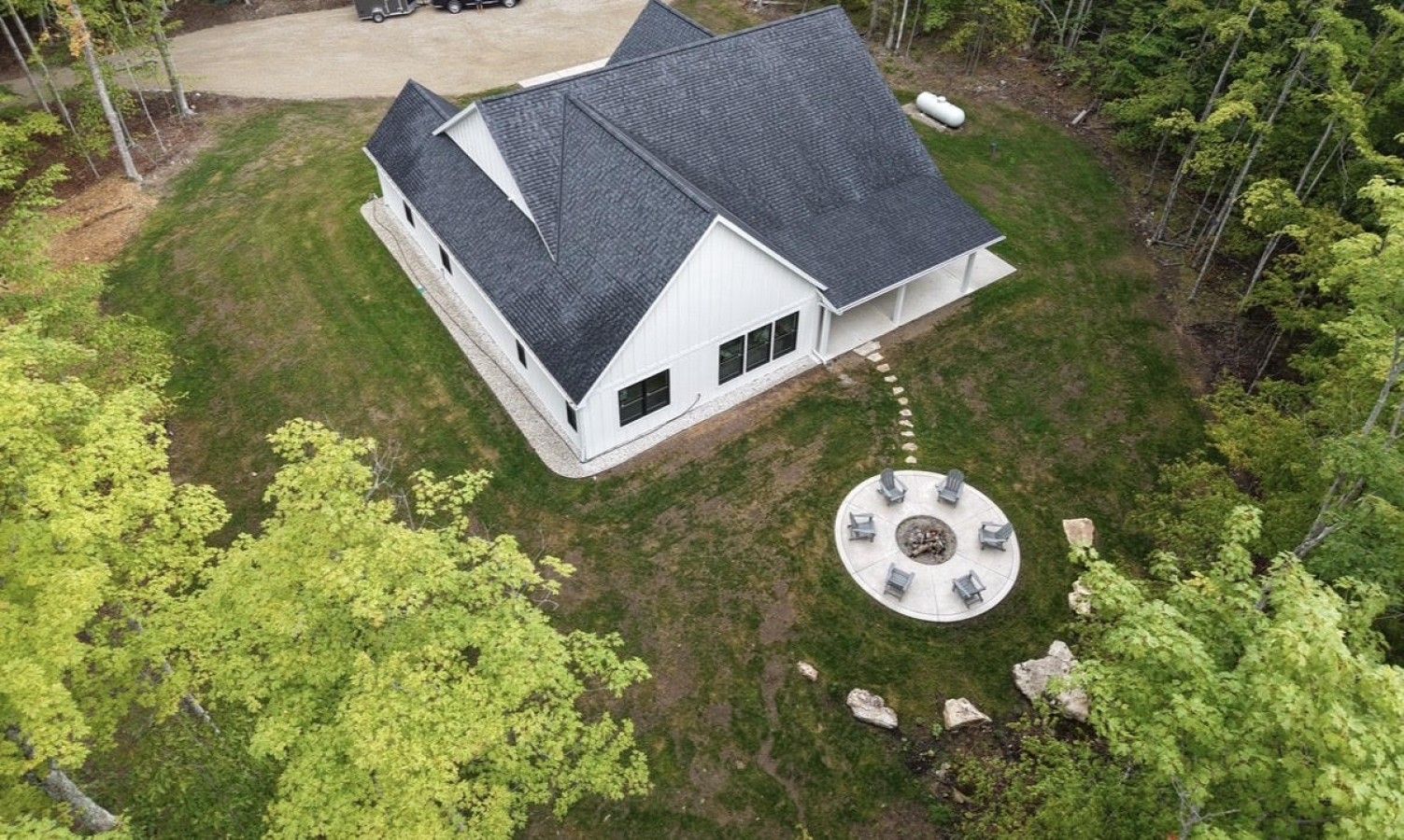 A two-story house with a circular outdoor seating area and a fire pit.