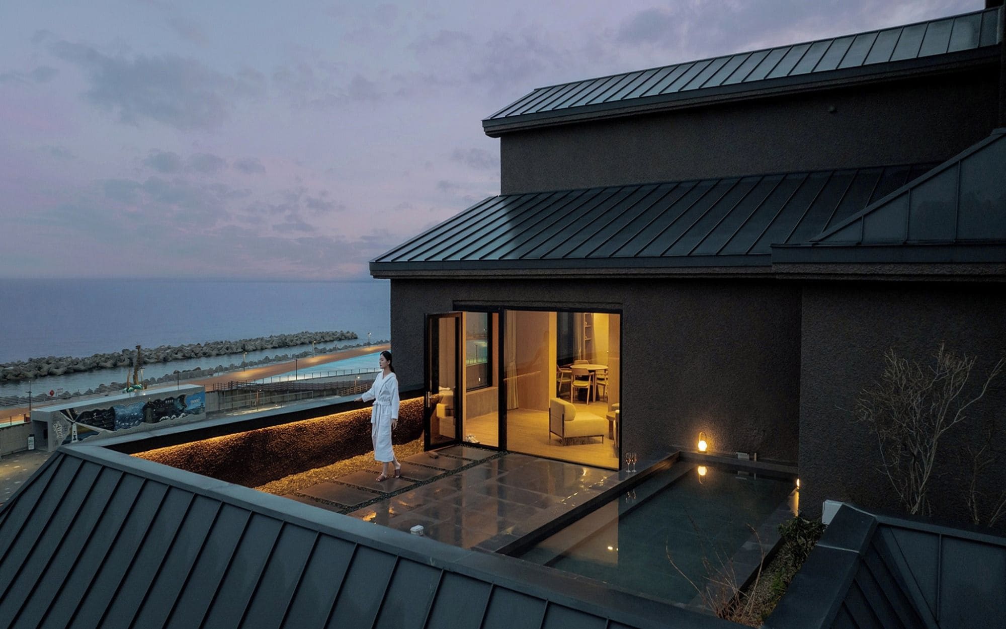 A modern building with a glass balcony overlooking a body of water.