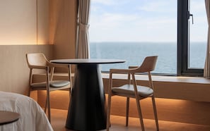 A hotel room with a round table and two chairs, a bed, and a view of the sea through a large window. - Gyeongju Hound The Pool Villa Gyeongju Gampo (Gyeongju)