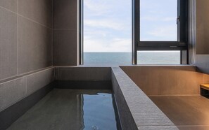 A modern bathroom with a large bathtub, a view of the sea, and a window. - Gyeongju Hound The Pool Villa Gyeongju Gampo (Gyeongju)