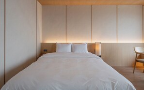 A modern hotel room with a large bed, a nightstand, a bedside table with a lamp, and a wooden chair. - Gyeongju Hound The Pool Villa Gyeongju Gampo (Gyeongju)