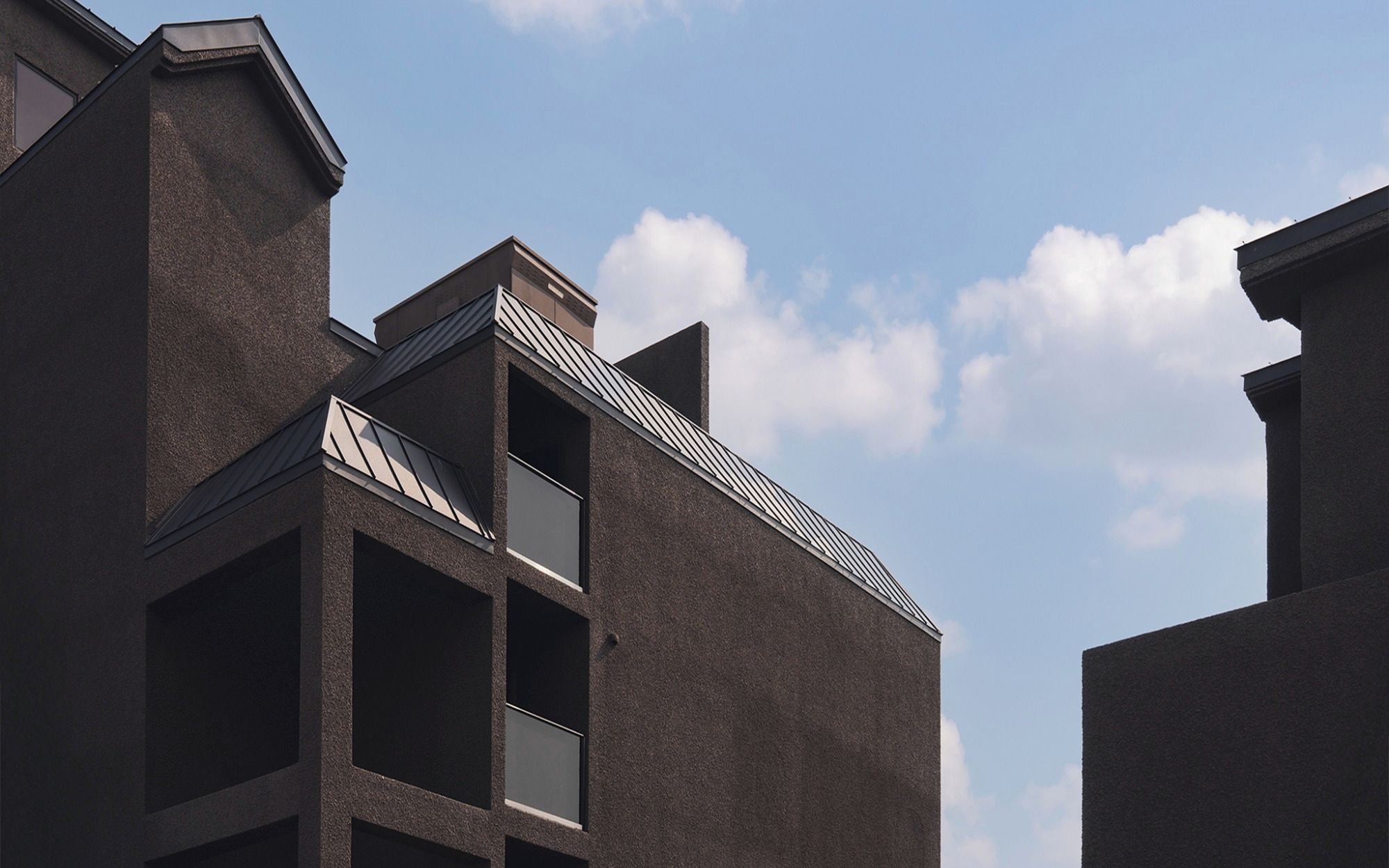 A modern building with a unique architectural design, featuring a prominent triangular roof and a balcony with a metal railing.