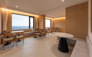 A modern interior with a seating area, tables, and a view of the sea. - Hound Steelcove Gyeongju Gampo (Gyeongju)